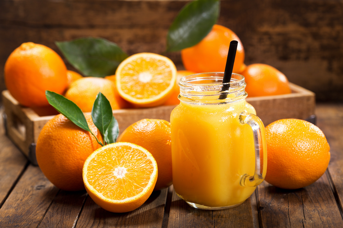 pot en verre de jus d'orange frais avec des fruits frais sur une table en bois