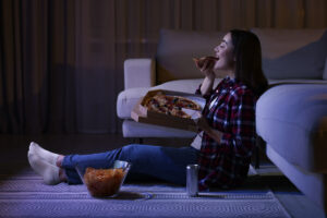 femme qui mange une pizza devant la tv