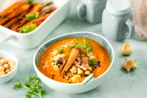 Pumpkin cream soup. Pumpkin and carrot puree soup with chickpeas and quinoa on a green background. Vegetarian cuisine. Vegan recipes.